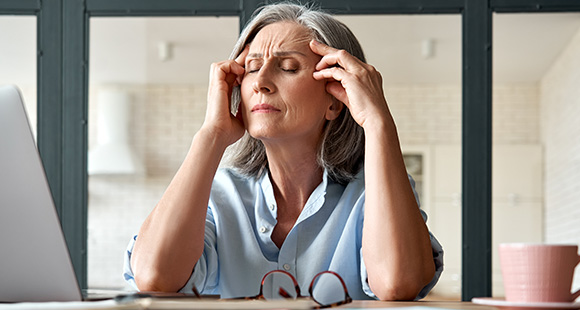 an older lady at work with a headache from menopause