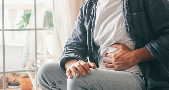 a man holding his hand to his stomach due to stomach pain